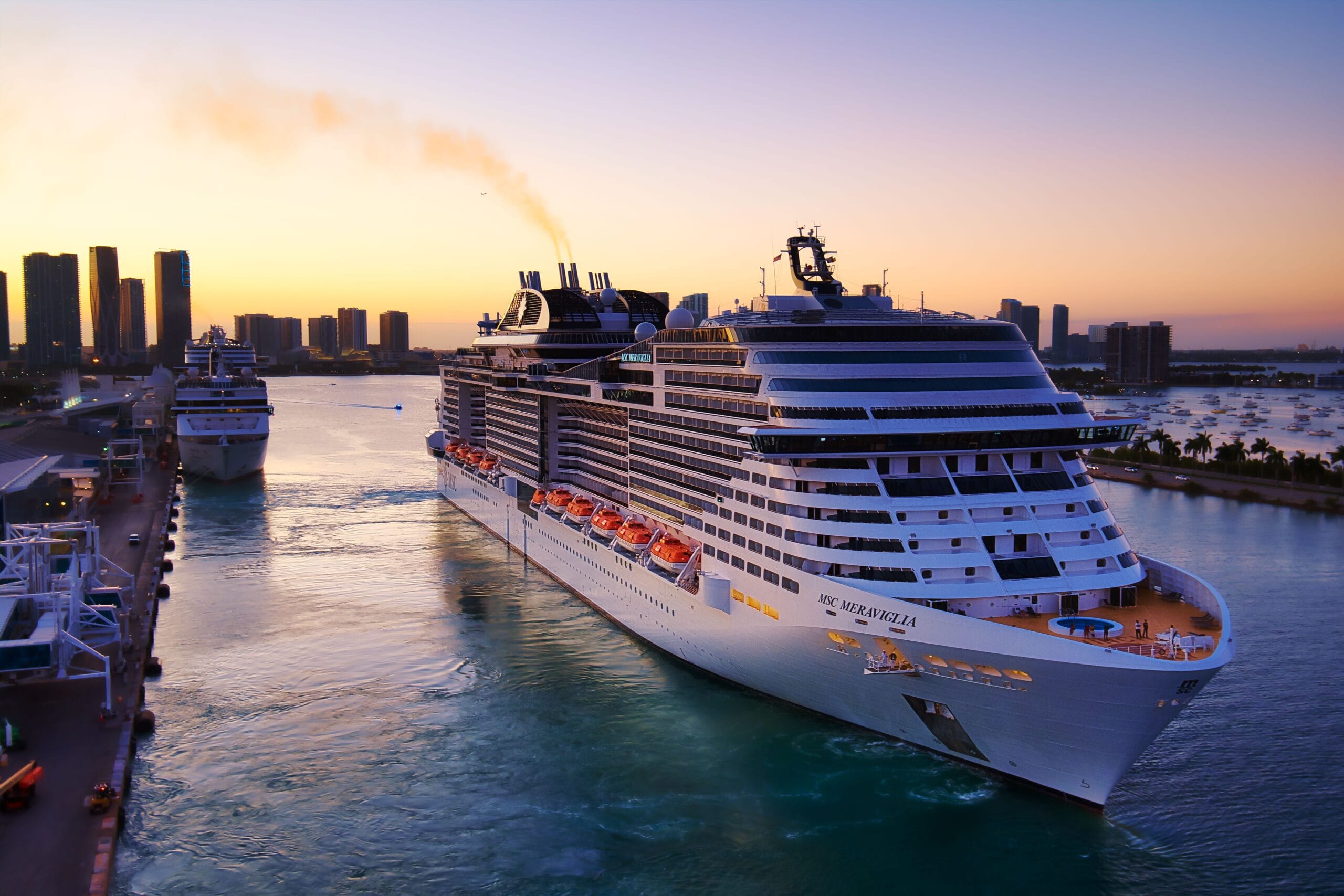 Miami Airport Transfers Stunning aerial view of cruise ships in Miami harbor at sunset, showcasing city skyline and vibrant colors.